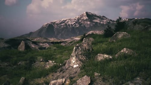 Mountain Landscape with Rocky Terrain and Grassy Foreground Under Cloudy Skies