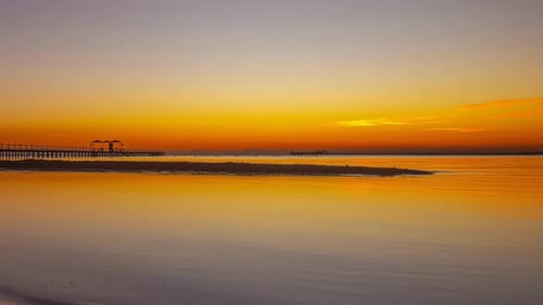 Golden Sunrise Over Calm Ocean Waters with Pier