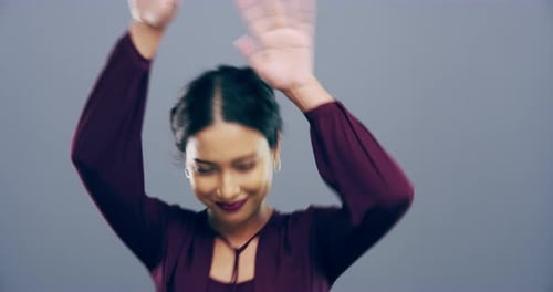 Eine junge Frau tanzt vor grauem Hintergrund