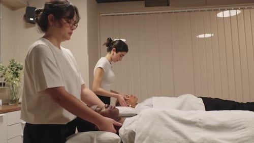 Massage Therapists Performing Neck and Face Massage in Spa Salon
