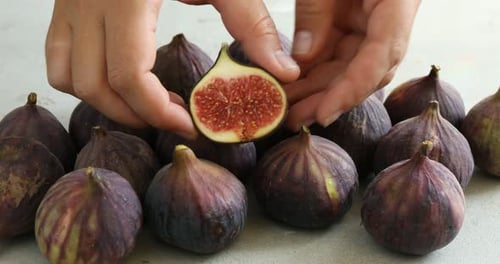 Woman breaking fig at gray table, closeup