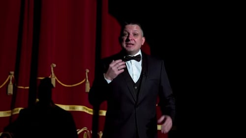 Actor on a stage. Adult man talks to the public in microphone or sings songs. Theater concept.