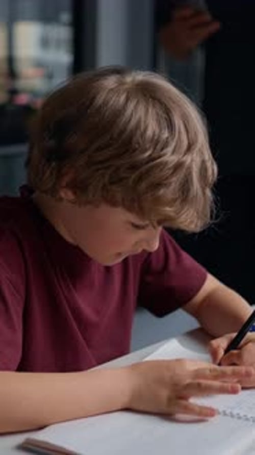 Focused Young Boy and Adult Man Both Engaged in Writing or Drawing Activities at a Table