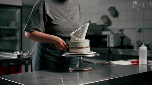 Female Baker in Professional Kitchen Wraps an Almost Finished Cake in Cling Film