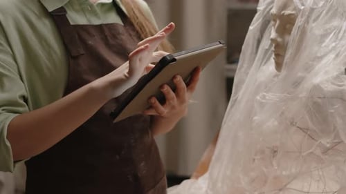 Unrecognizable Sculptor Using Digital Tablet in Workshop