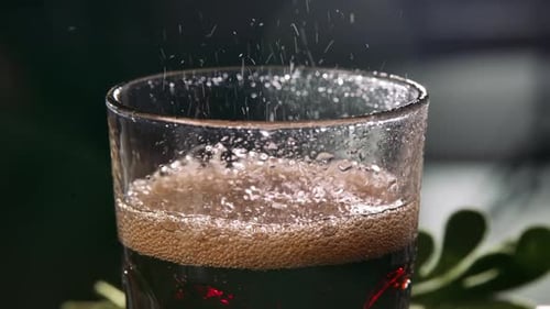 Rotating Transparent Glass with Dark Sweet Liquid and Leaping Bubbles. Beautiful