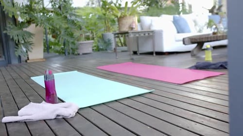 Water bottle, towel and exercise mats on sunny terrace