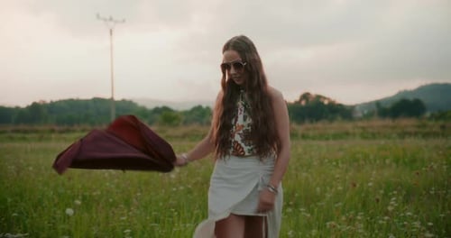 Woman Walking Through Grassy Field at Sunset