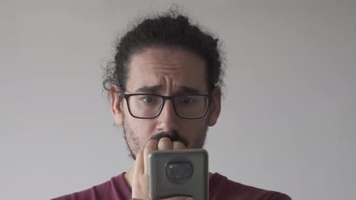 Close up of anxious man looking at smartphone and biting his nails
