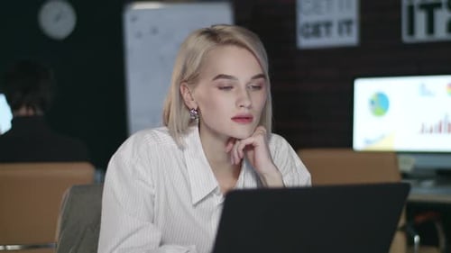 Thoughtful business woman works late night overtime in dark corporate office