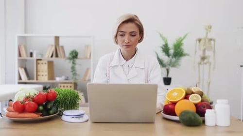 Woman working with laptop at nutritionist desk