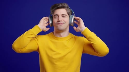 Man enjoying music with headphones on blue background
