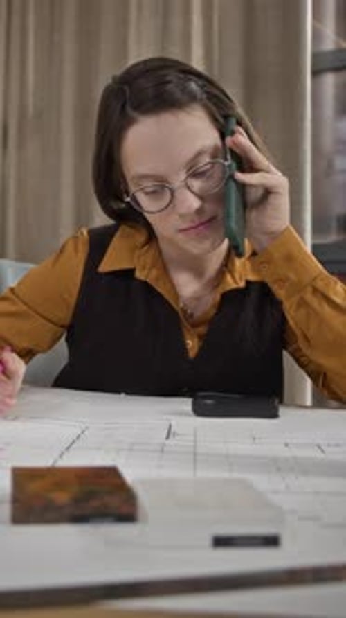Vertical of Young Woman on Phone Reviewing Architectural Blueprint