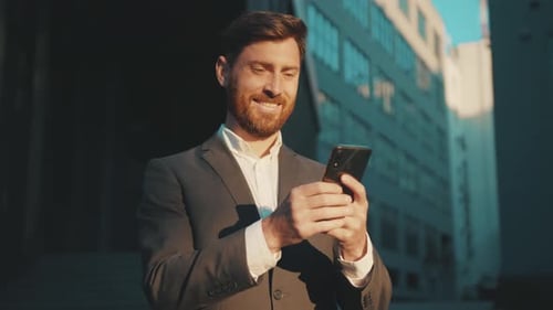 Happy Businessman Stand in the City Center Street Uses Phone Texting Scrolling Tapping Smile