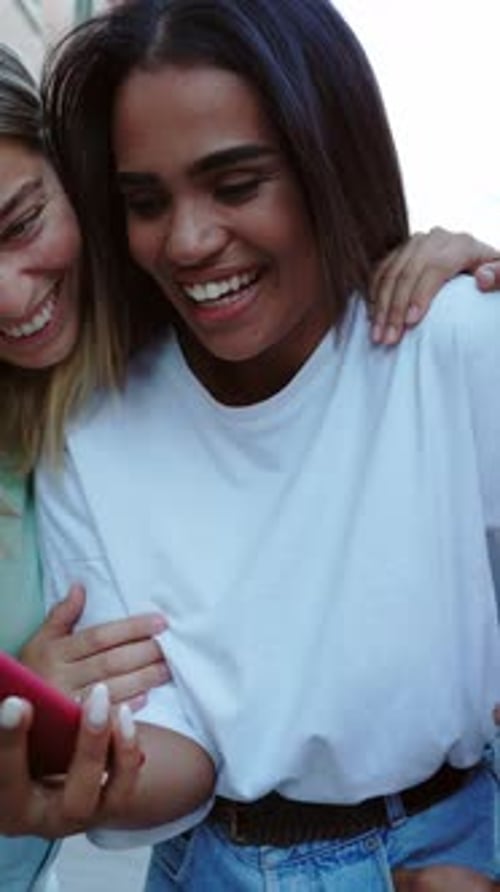 Young Happy Female Friends Having Fun Using Mobile Phone at City Street