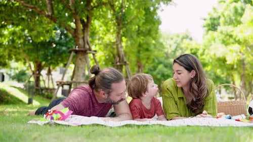 Caucasian family, parents children, was lying face down on mat spread on grass in garden near house,