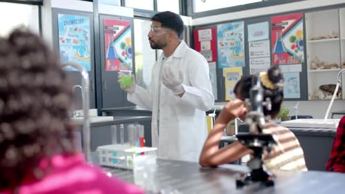 In a school chemistry lab, a biracial teacher engages young students