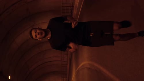 Running concept. Portrait of sportive man runs along tunnel. Vertical video