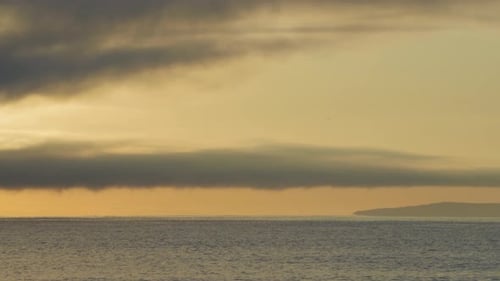 Black Sea and Beach Nearby Against a Sky with Clouds and a Dawn Sun