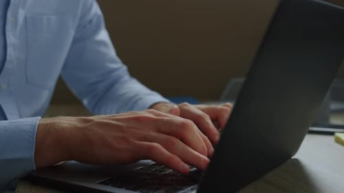 Красивый бизнесмен печатает сообщение на клавиатуре ноутбука на рабочем месте