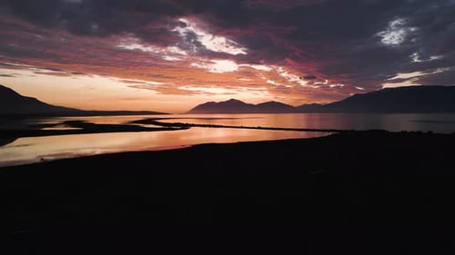 Golden Hour Over Calm Water and Distant Mountains at Sunset