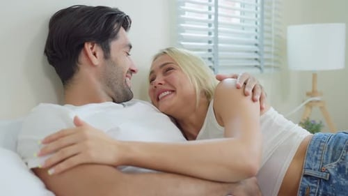 Kaukasisches neues Ehepaar liegt auf dem Bett und schaut sich an.