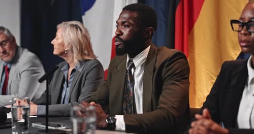 People Speaking at a Press Conference with Flags