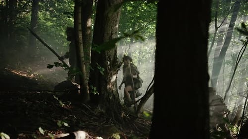 Une tribu de chasseurs-cueilleurs portant une peau d'animal tenant des outils à pointe de pierre explore les forêts préhistoriques