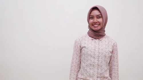 Happy Wow Excited Young Asian muslim woman standing while pointing and presenting sideways. Isolated