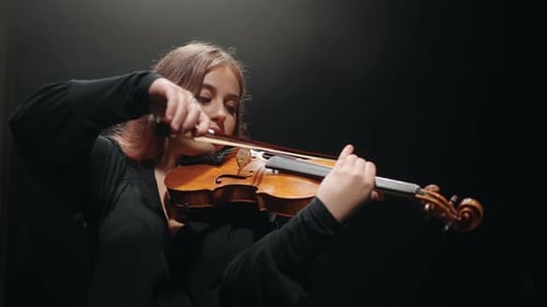 Inspired Female Violinist is Playing Violin in Music School or Dark Music Hall Musician is Playing