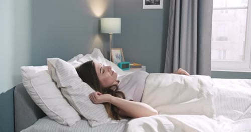 Young Woman Wakes Up, Stretches in Bed