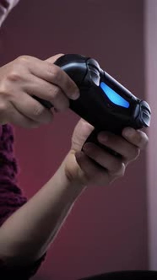 Hands holding joystick of game console and pressing buttons. Vertical video
