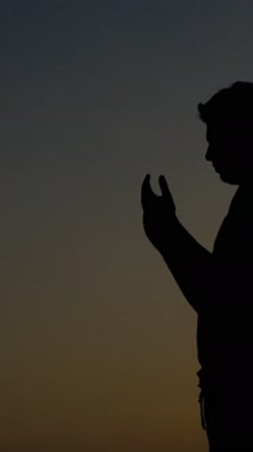 Silhouette of Young Adult in Prayer at Sunset