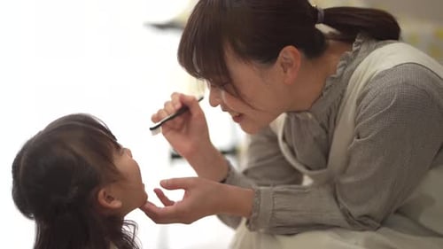 Smiling Mother Brushing Child's Teeth Indoors