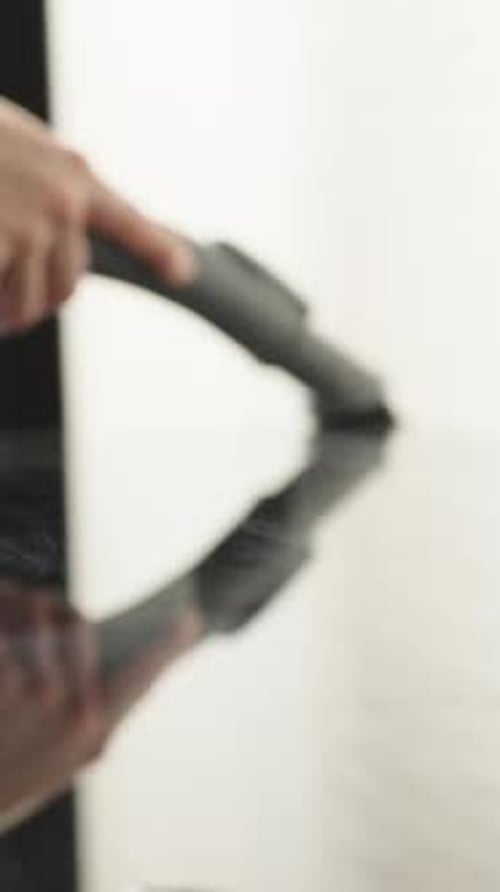 The woman is vacuuming the black glass table, it is covered in dust. Close-up Vertical video.