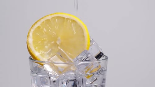 Sparkling Water Poured into a Glass with Lemon and Ice