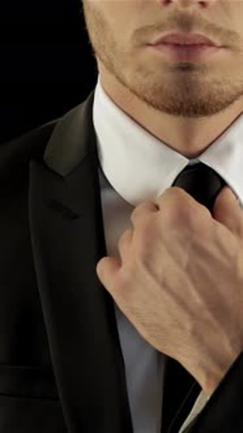 Man Adjusting His Tie in a Black Suit
