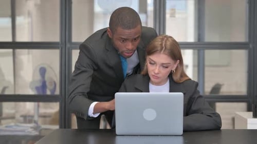 Businesswoman working with coworker at laptop in office