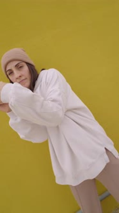 Danseuse de hip hop faisant des rainures contre un mur jaune vif