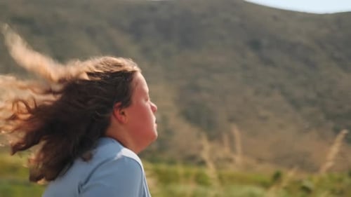 Tired Teenage Girl Runs Through a Green Field Pushing to Improve Fitness
