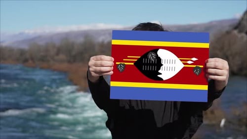 Person Holding Eswatini Flag in Mountain Landscape