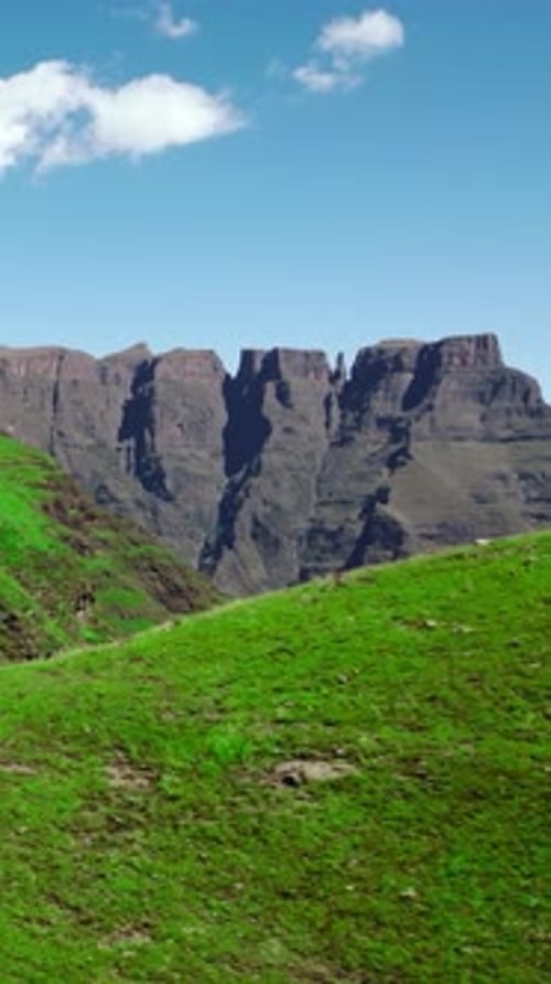 Green Hillside Beneath Blue Sky Peaceful Rolling Green Hills Topped With Rugged Cliffs And Clouds