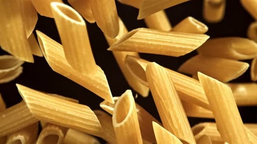 Penne Pasta Falling in Slow Motion Against Black