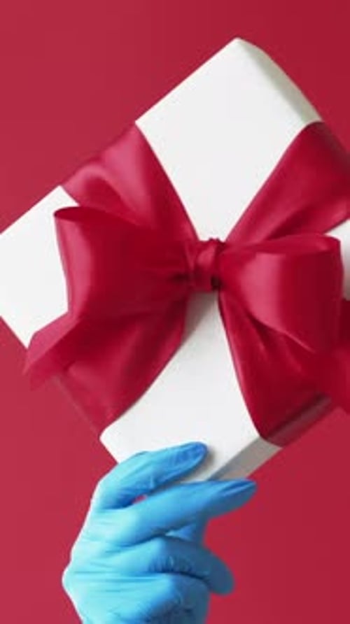 Hand Holds Gift Box on Red Background