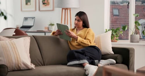 Woman Relaxes on Sofa Using a Tablet Device