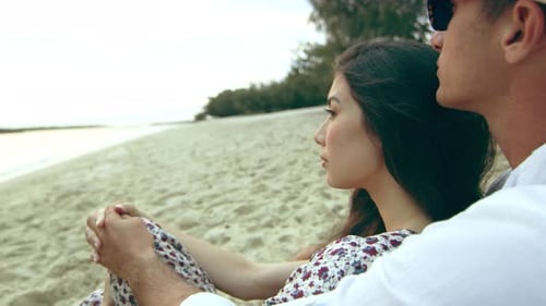 Relaxed Young Couple, Cuddling on the Beach, Laying in the Sand, Looking