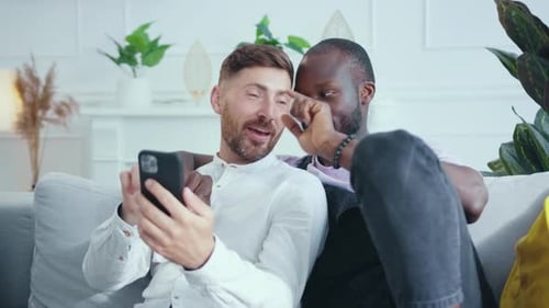 Loving Male Couple Using a Mobile Phone on Sofa