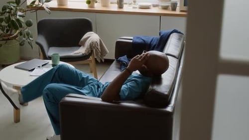 Medical Professional Resting on Couch After Long Shift