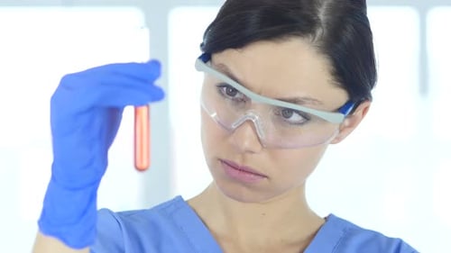 Primer plano de un científico que estudia una solución roja en un tubo de ensayo