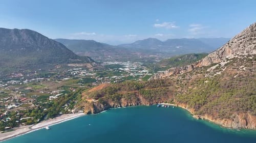 Türkisfarbenes Wasser, das gegen einen schroffen Berg plätschert, sorgt für eine ruhige Szenerie, Sonnenlicht umhüllt die Pisten